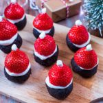 A wooden serving board with nine Santa Hat Brownies