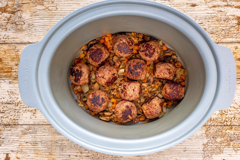 A slow cooker pot with cooked meatballs.