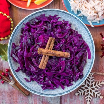 A bowl of slow cooker red cabbage topped with two crossed cinnamon sticks
