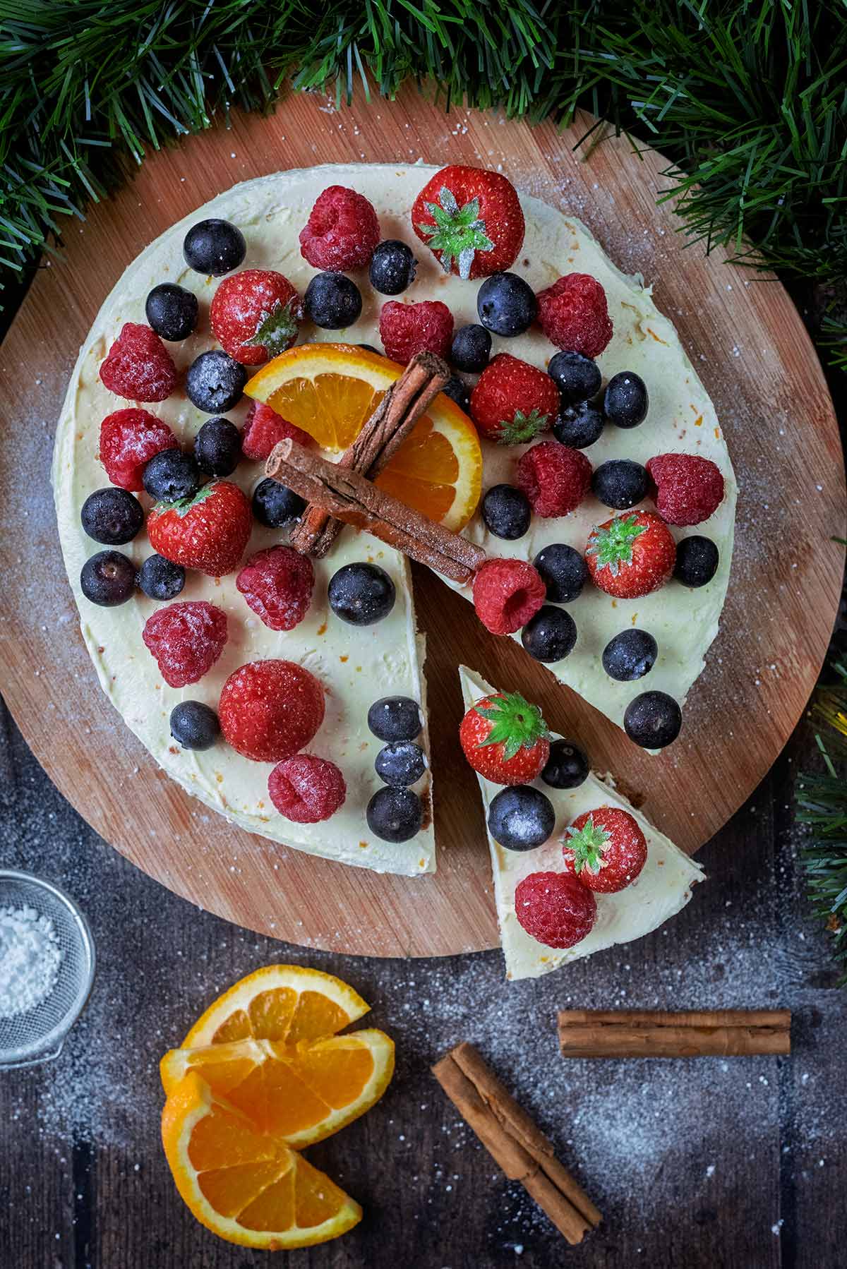 A cheesecake topped with berries and a slice removed.