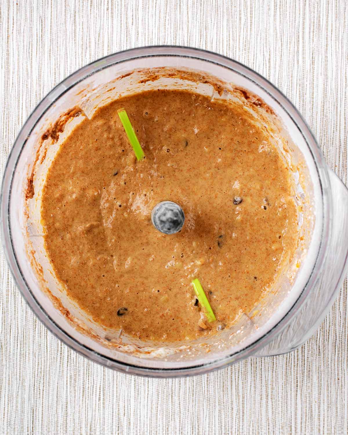 A food processor containing a brown cake batter.