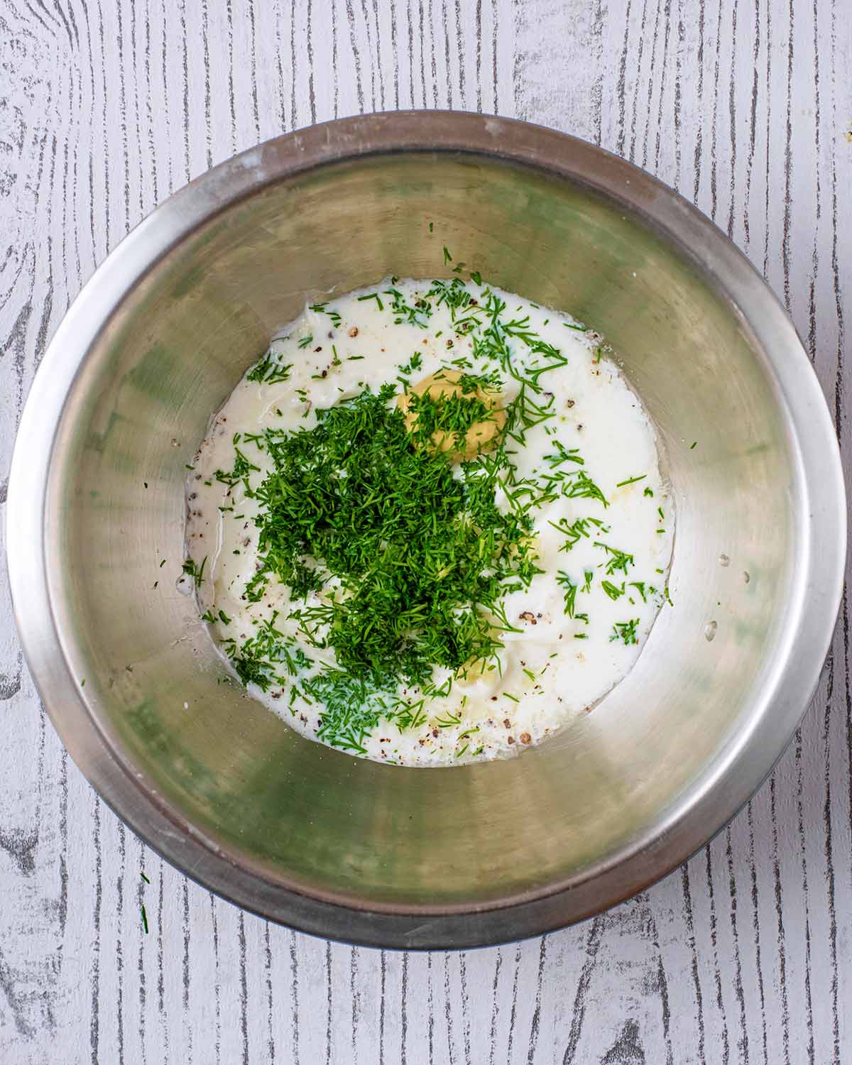 A mixing bowl containing the ingredients for ranch dressing.