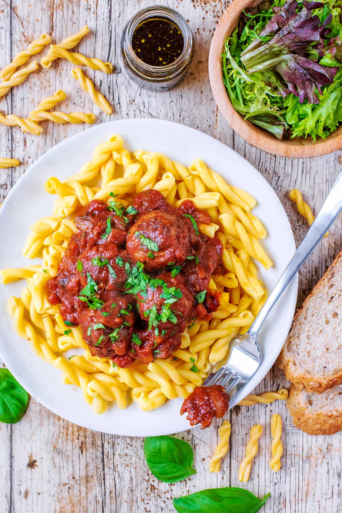 A plate of Slow Cooker Meatballs next to a small bowl of salad.