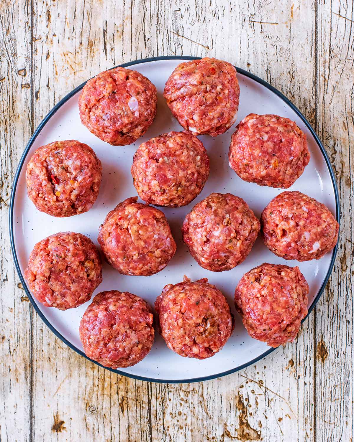 Twelve meatballs on a white plate.