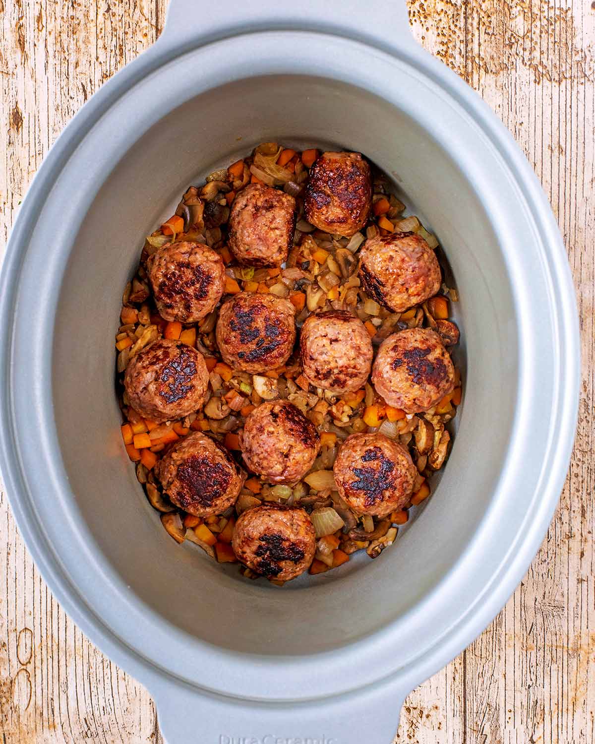 A slow cooker pot with cooked meatballs.