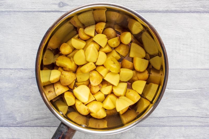 A saucepan containing uncooked cubed potatoes.