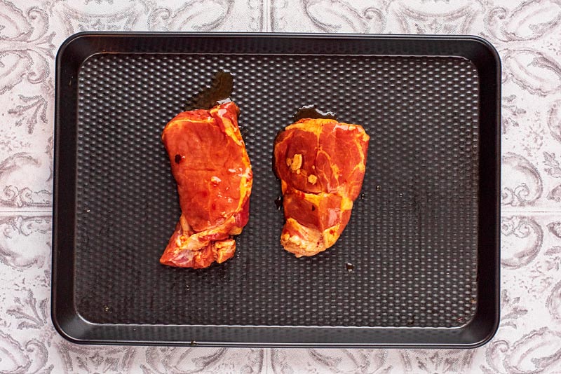 A baking tray with two marinated pork loins.