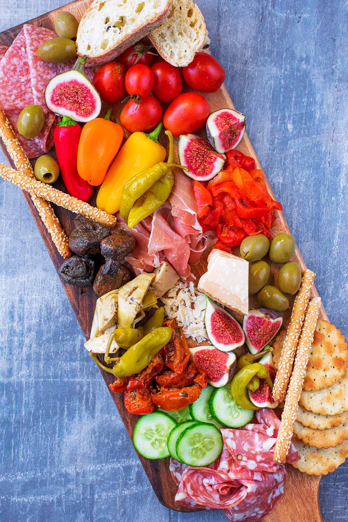 A mix of antipasto on a long wooden board.