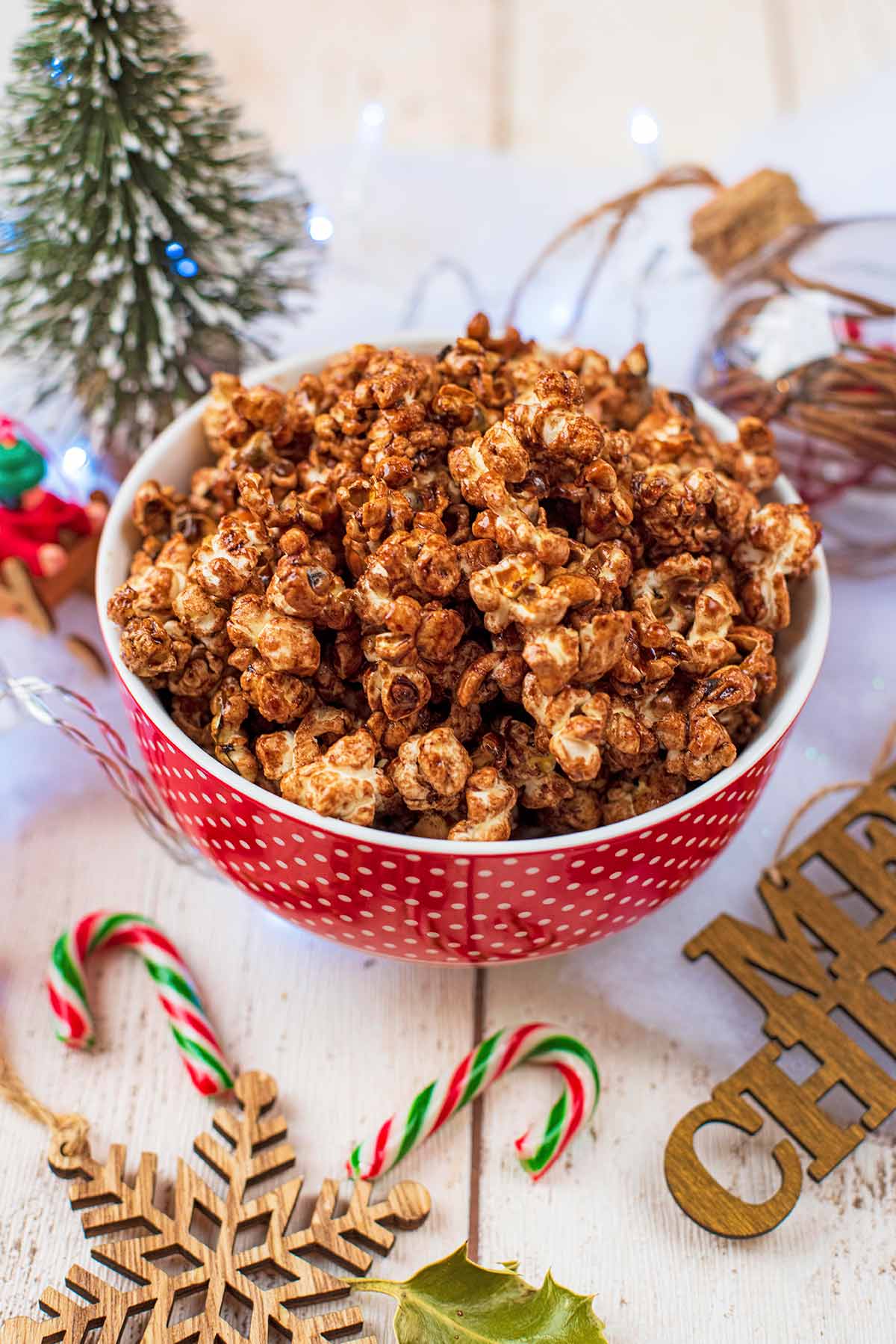 Popcorn in a red bowl next to Christmas decorations.