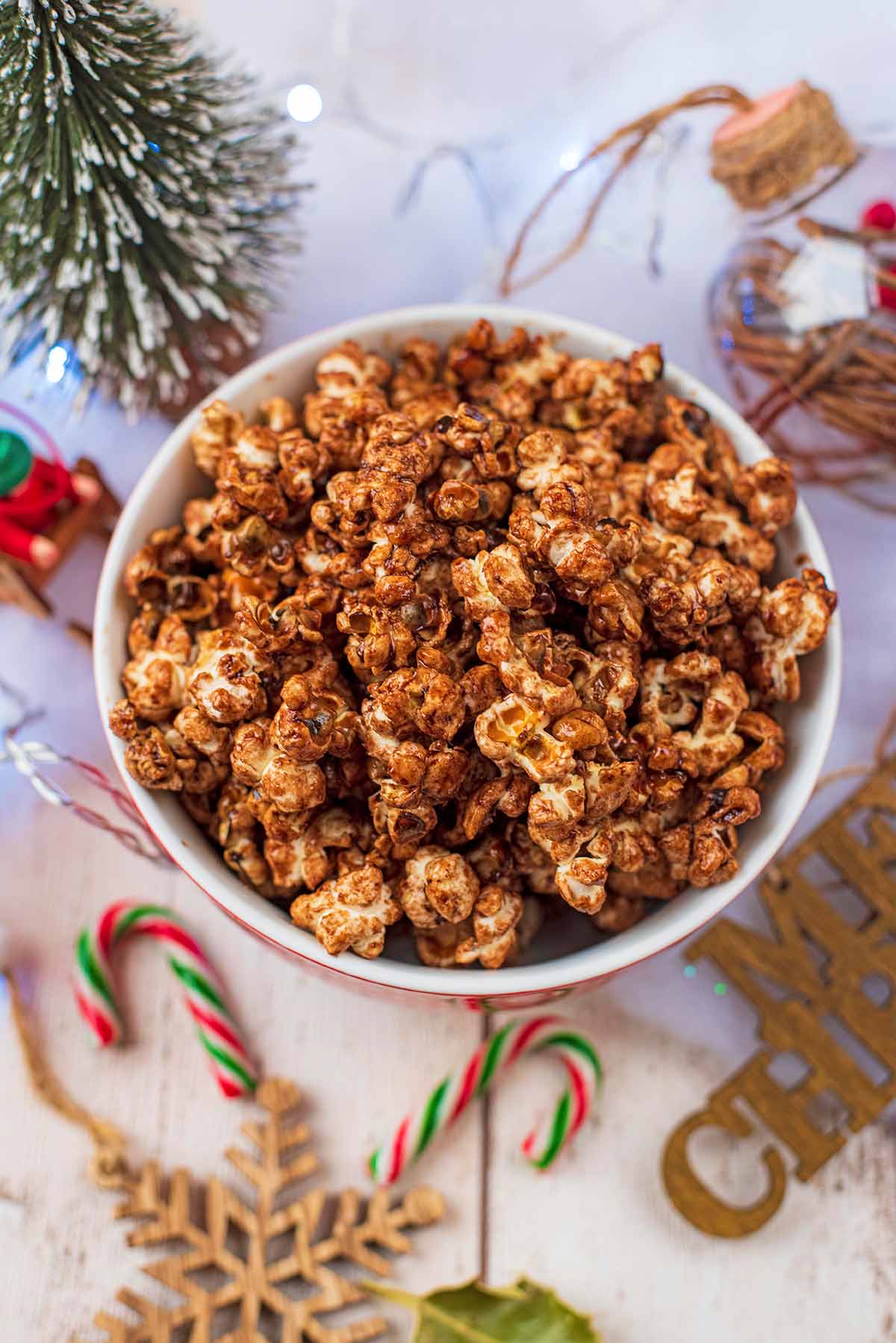 A bowl of popcorn next to Christmas decorations.