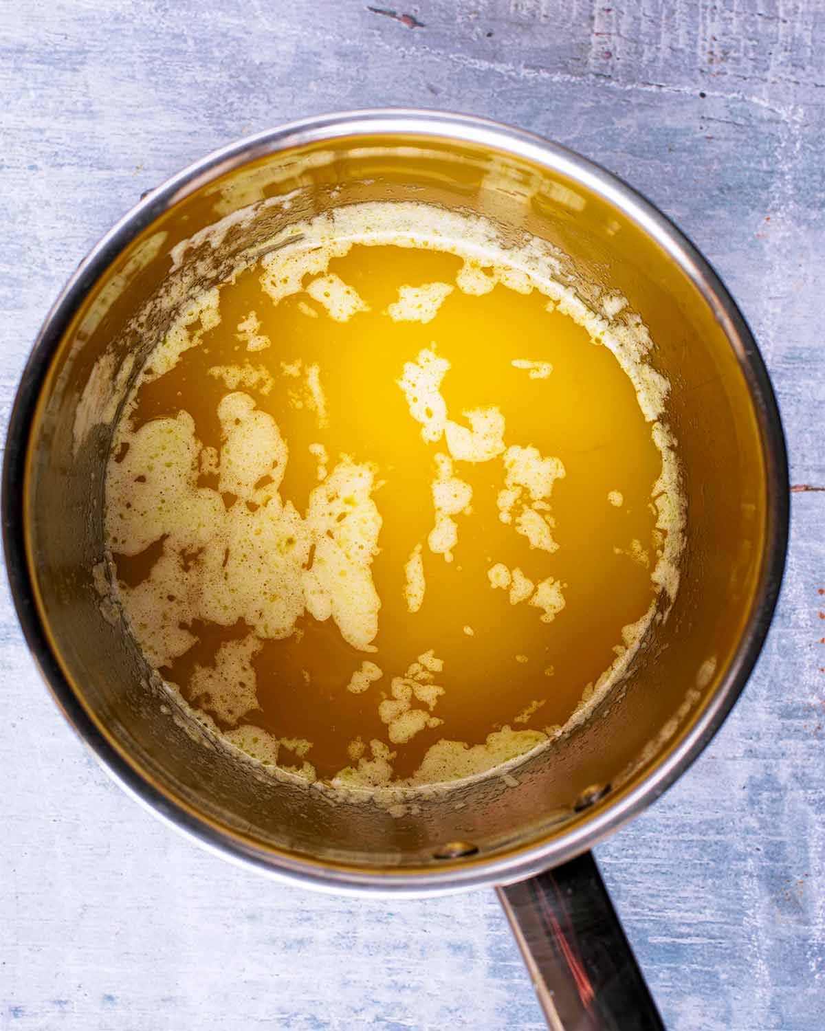 a stainless steel saucepan containing melted butter.