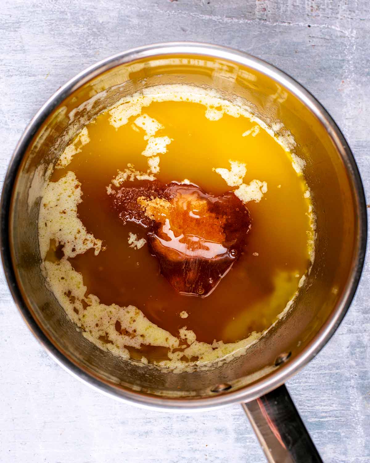 A stainless steel saucepan containing melted butter, sugar and golden syrup.