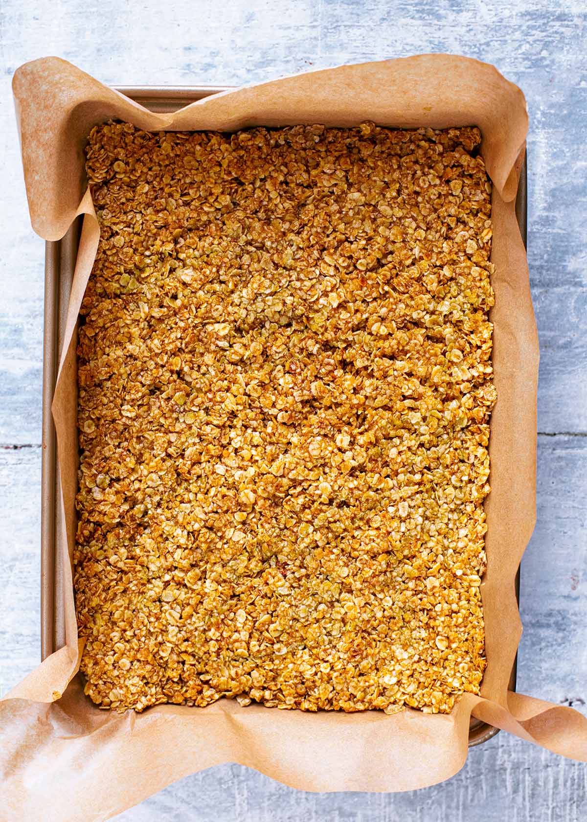 A lined baking tray containing a slab of flapjack.