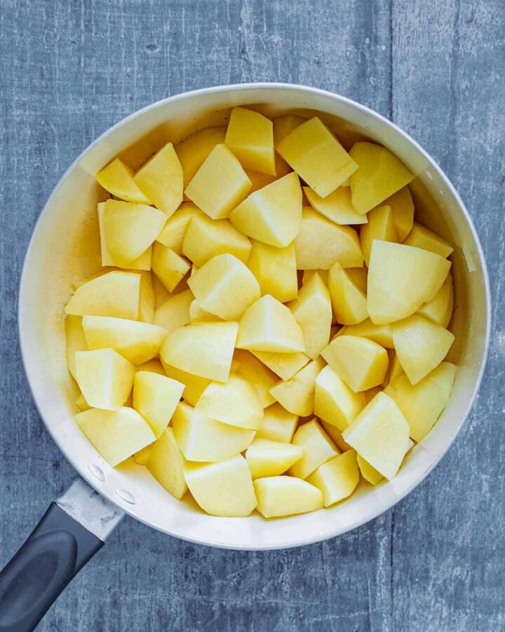 A saucepan containing chunks of chopped potatoes.