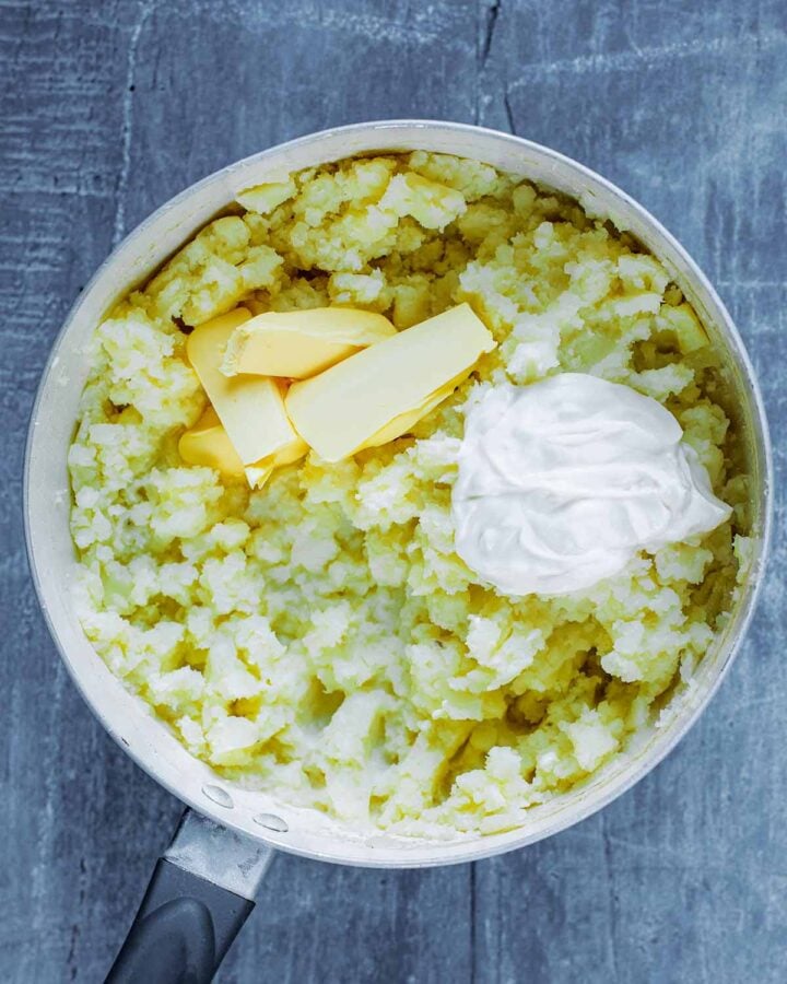 A saucepan containing mashed potato, butter and cream.