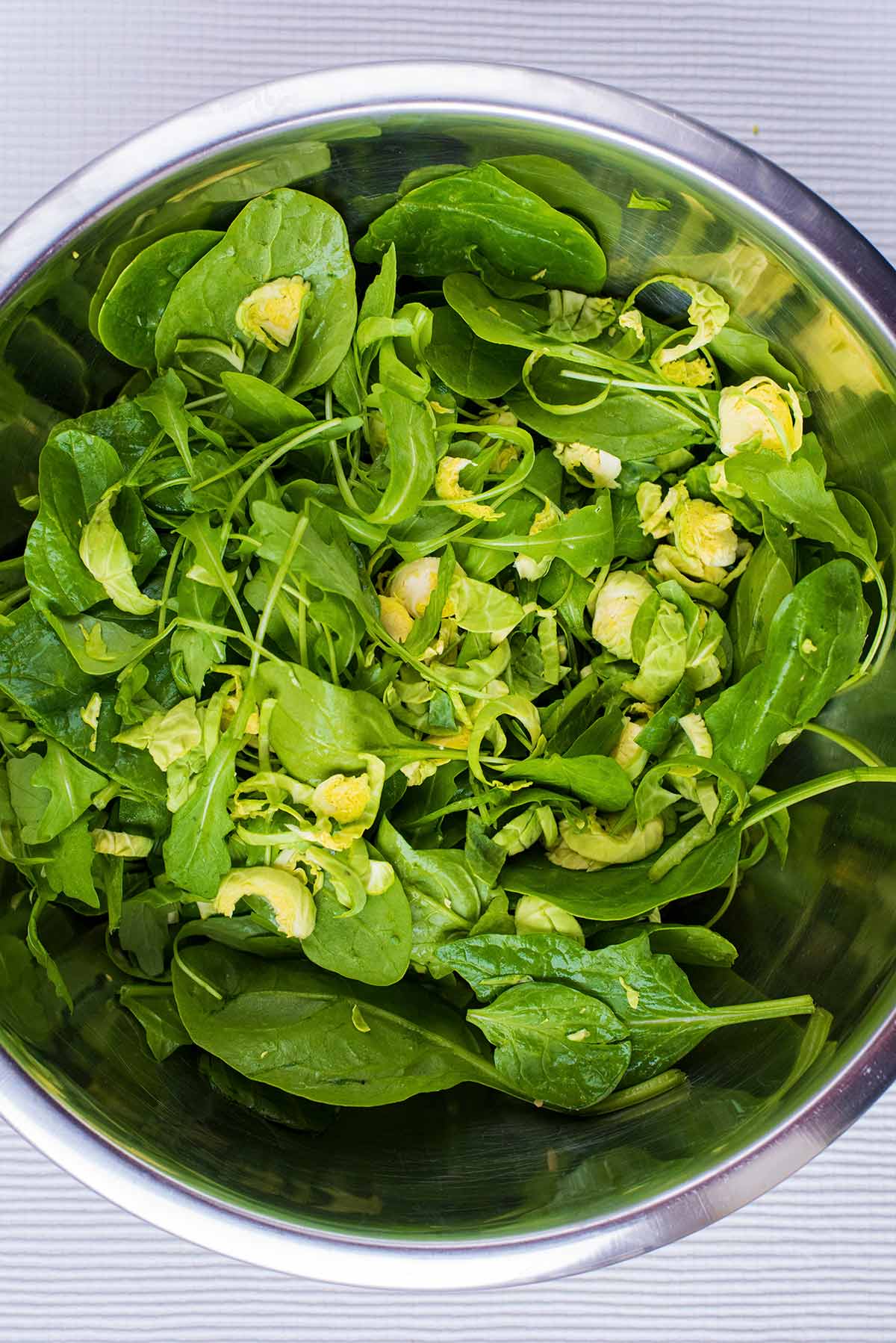 A large metal bowl containing salad leaves.