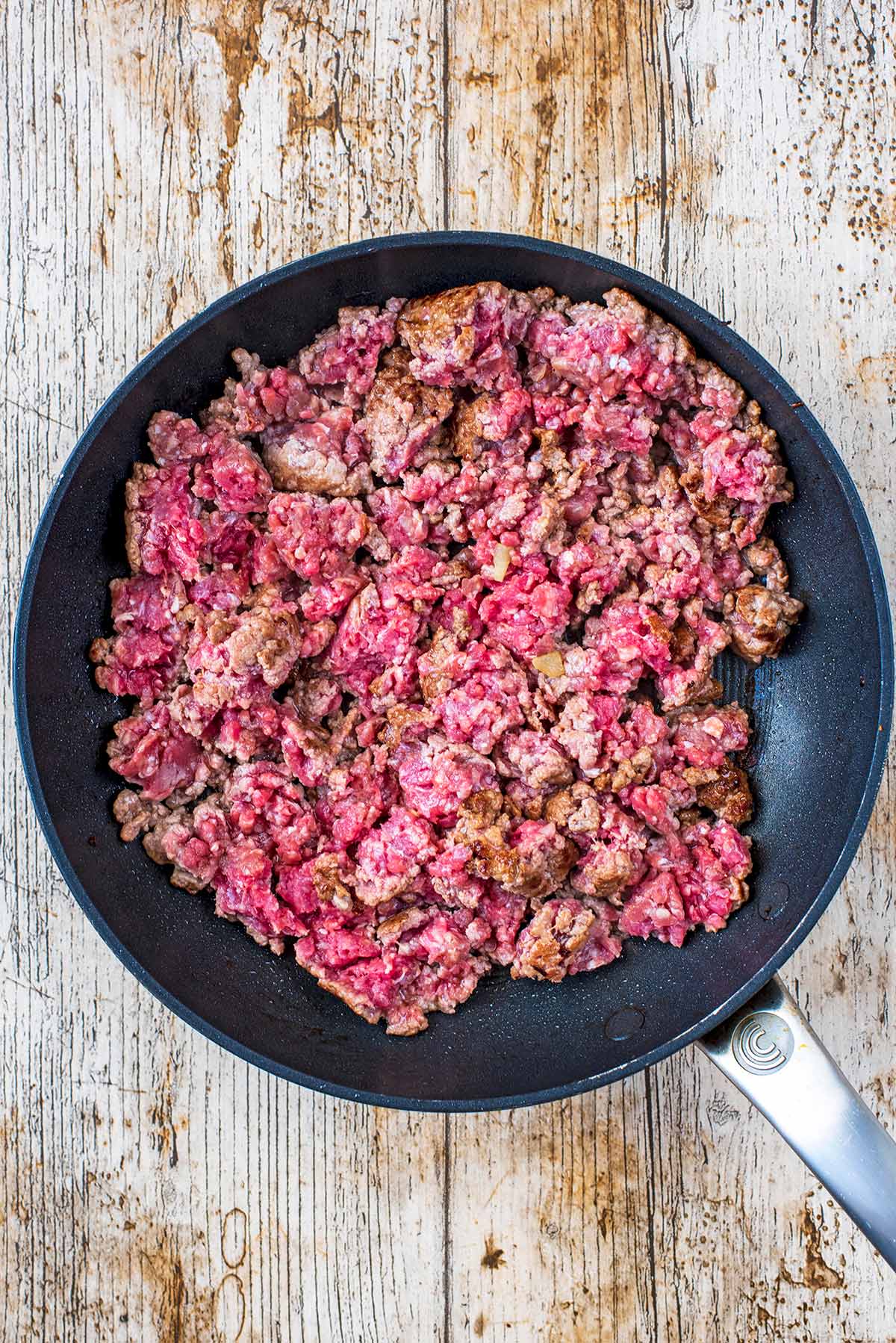 A frying pan with part cooked beef mince.