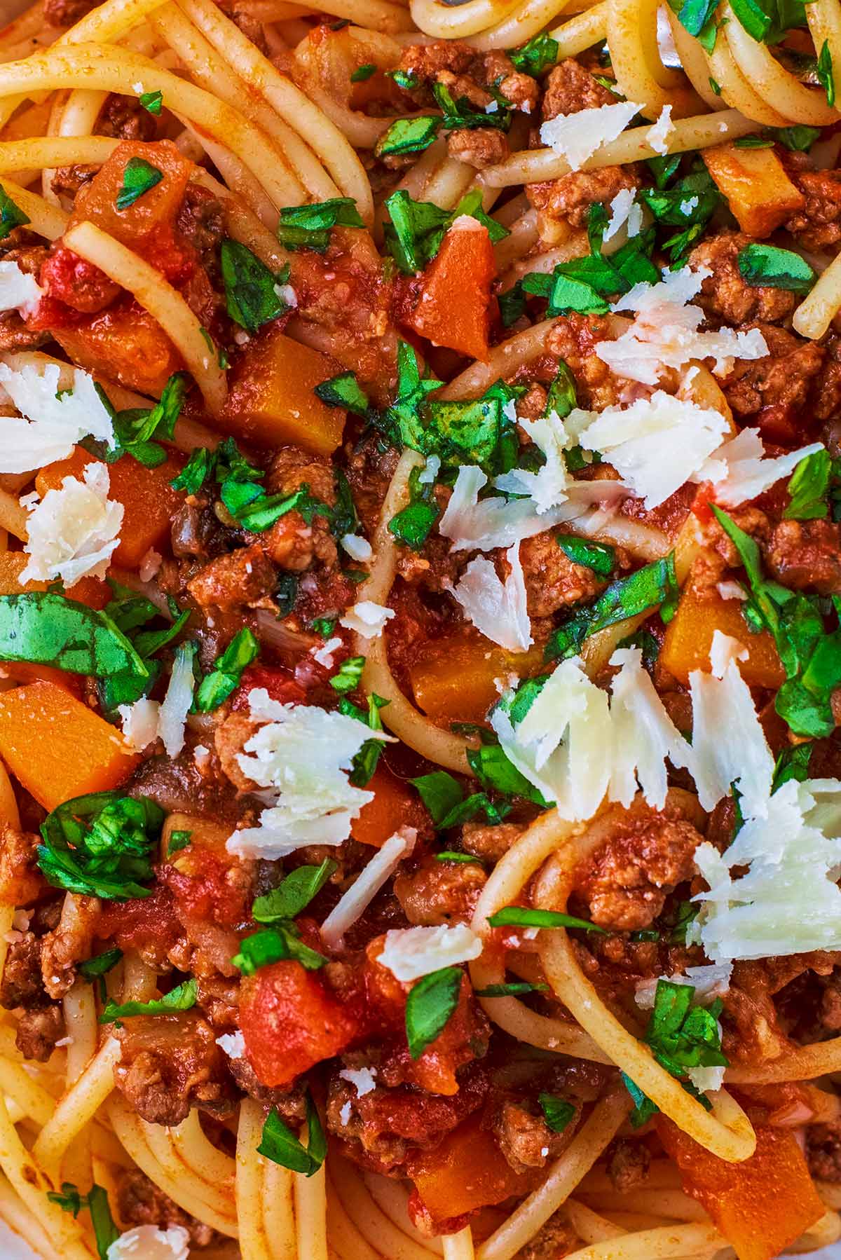 Bolognese mixed with spaghetti, topped with basil and Parmesan.