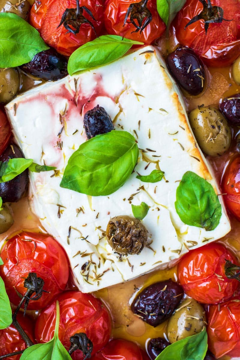 A block of baked feta cheese surrounded by roasted cherry tomatoes.