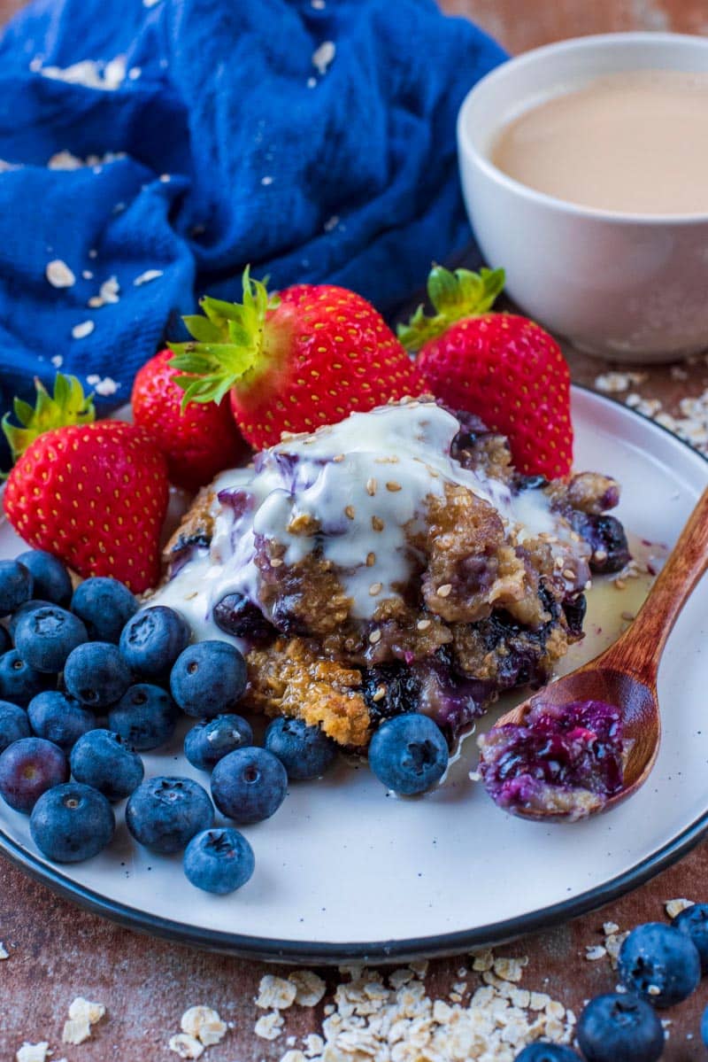 Baked oats, berries and a small spoon on a white plate.