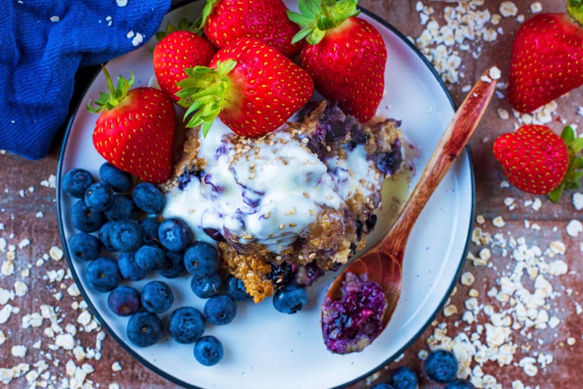 Easy Baked Oats on a white plate with fruit and a spoon.