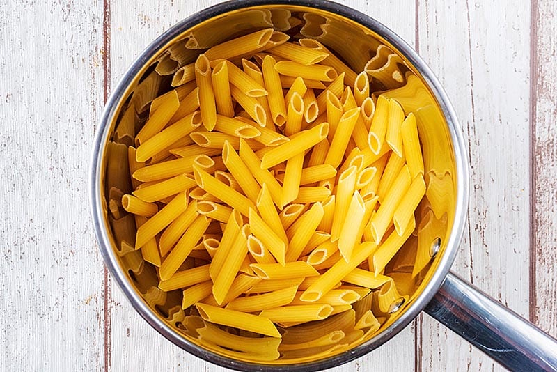 A stainless steel saucepan containing penne pasta