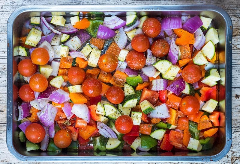 A large roasting tin with chopped vegetables.