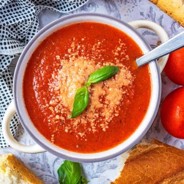 Tomato and Basil Soup topped with grated cheese and two basil leaves.