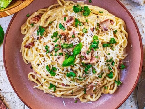 A bowl of healthy carbonara with small basil leaves on top.