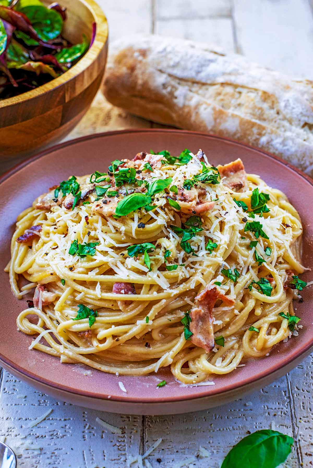 Spaghetti Carbonara on a plate with chopped basil leaves sprinkled on top.