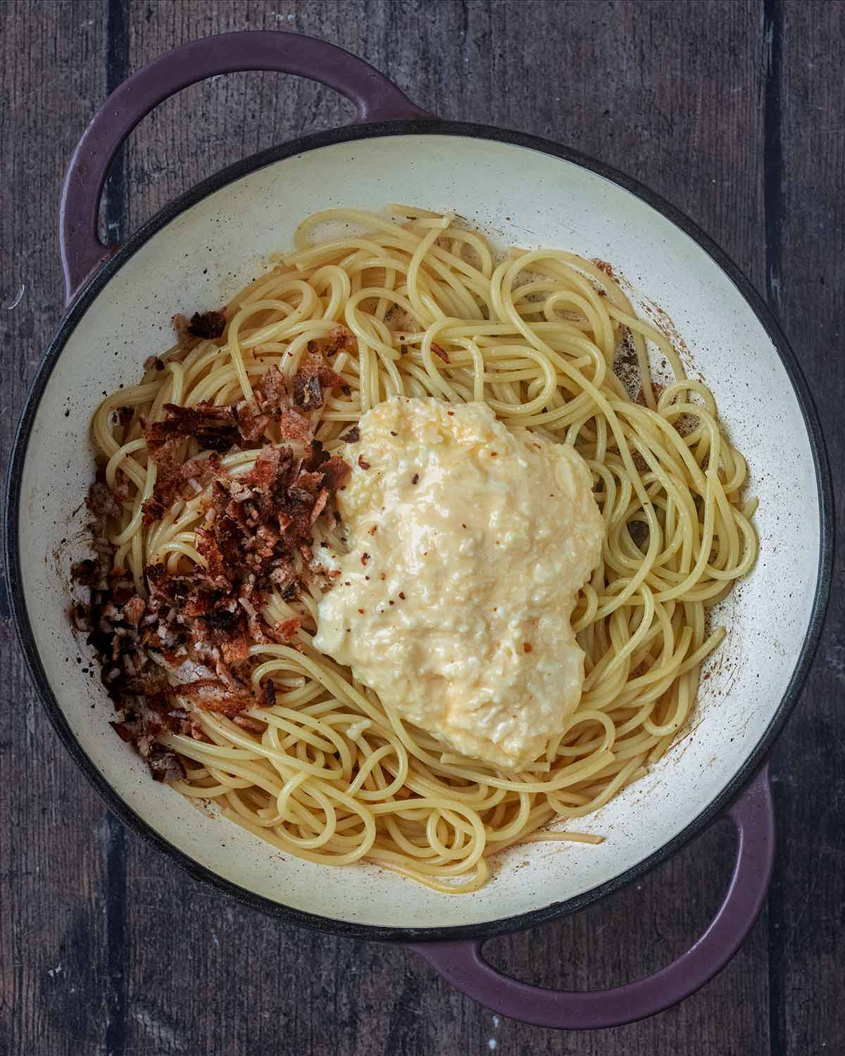 Cooked spaghetti, chopped bacon and the egg mixture in the large pan.