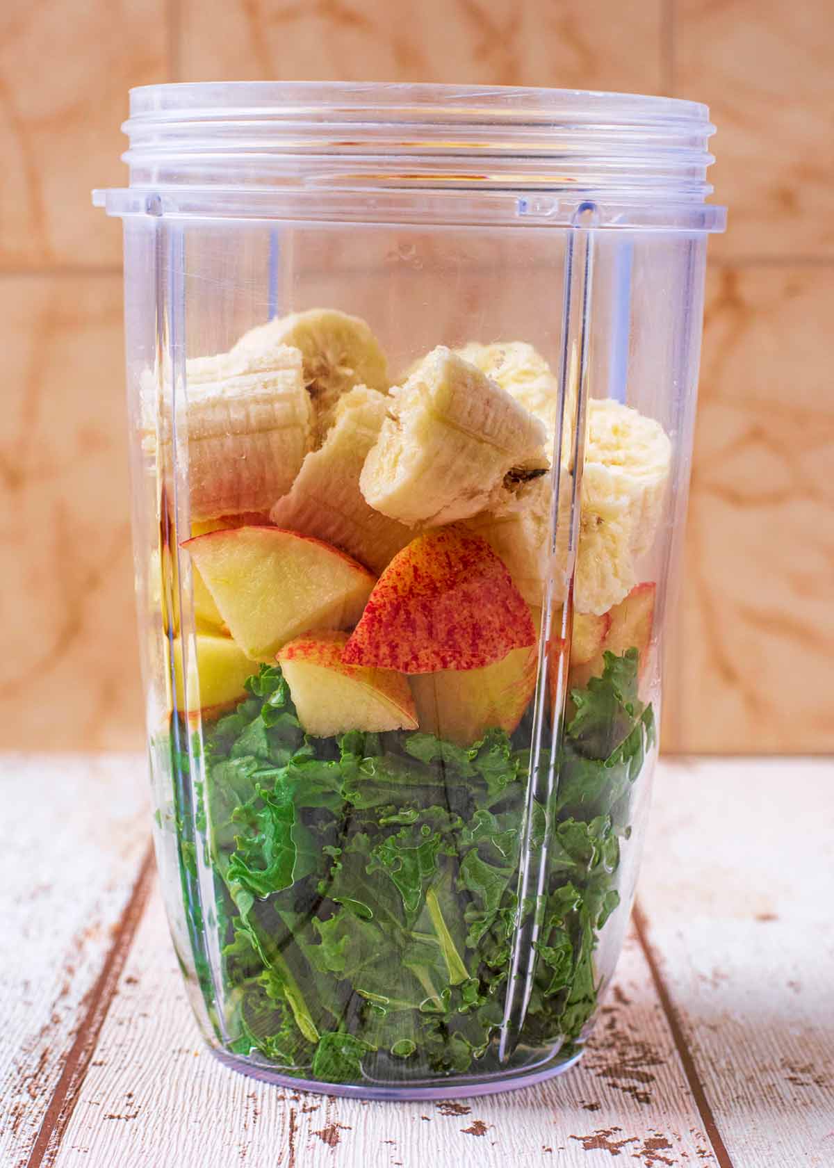 Kale leaves, sliced banana and chunks of apple in a blender jug.