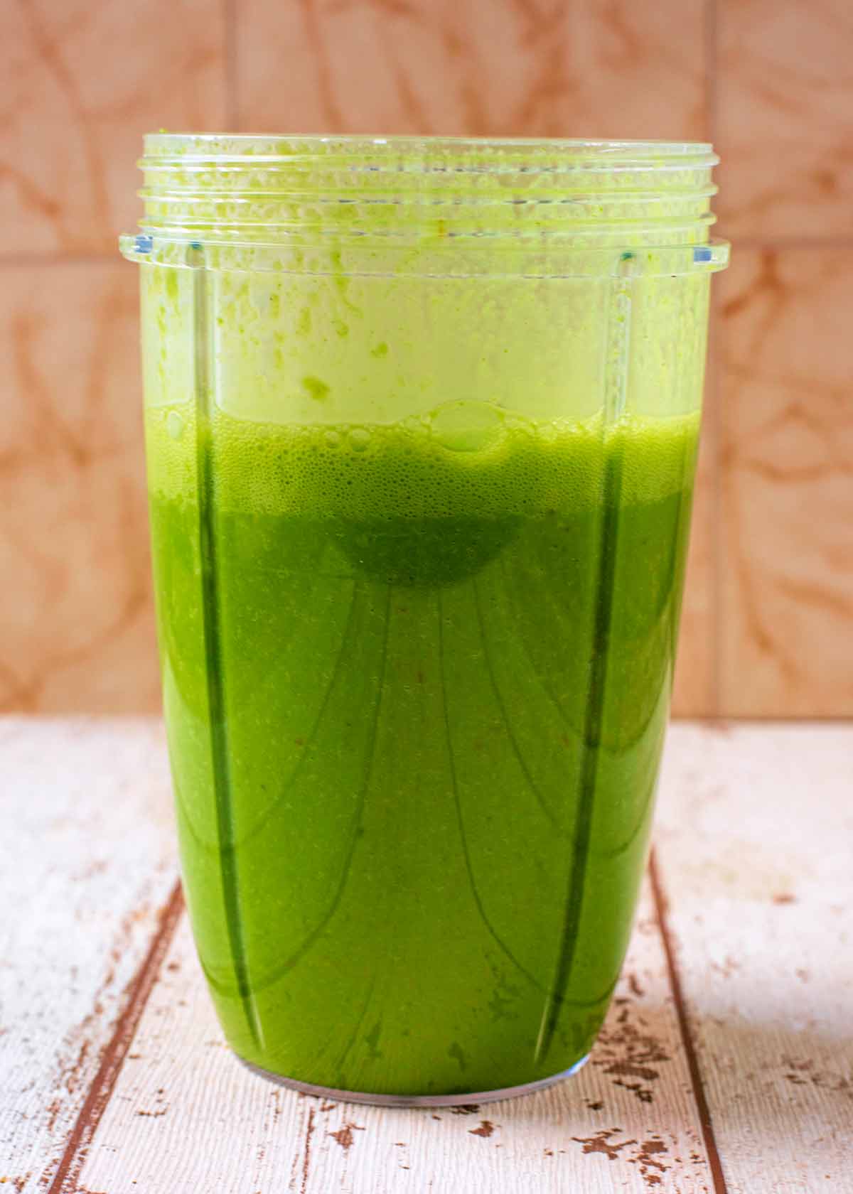 A blended green smoothie in a blender jug