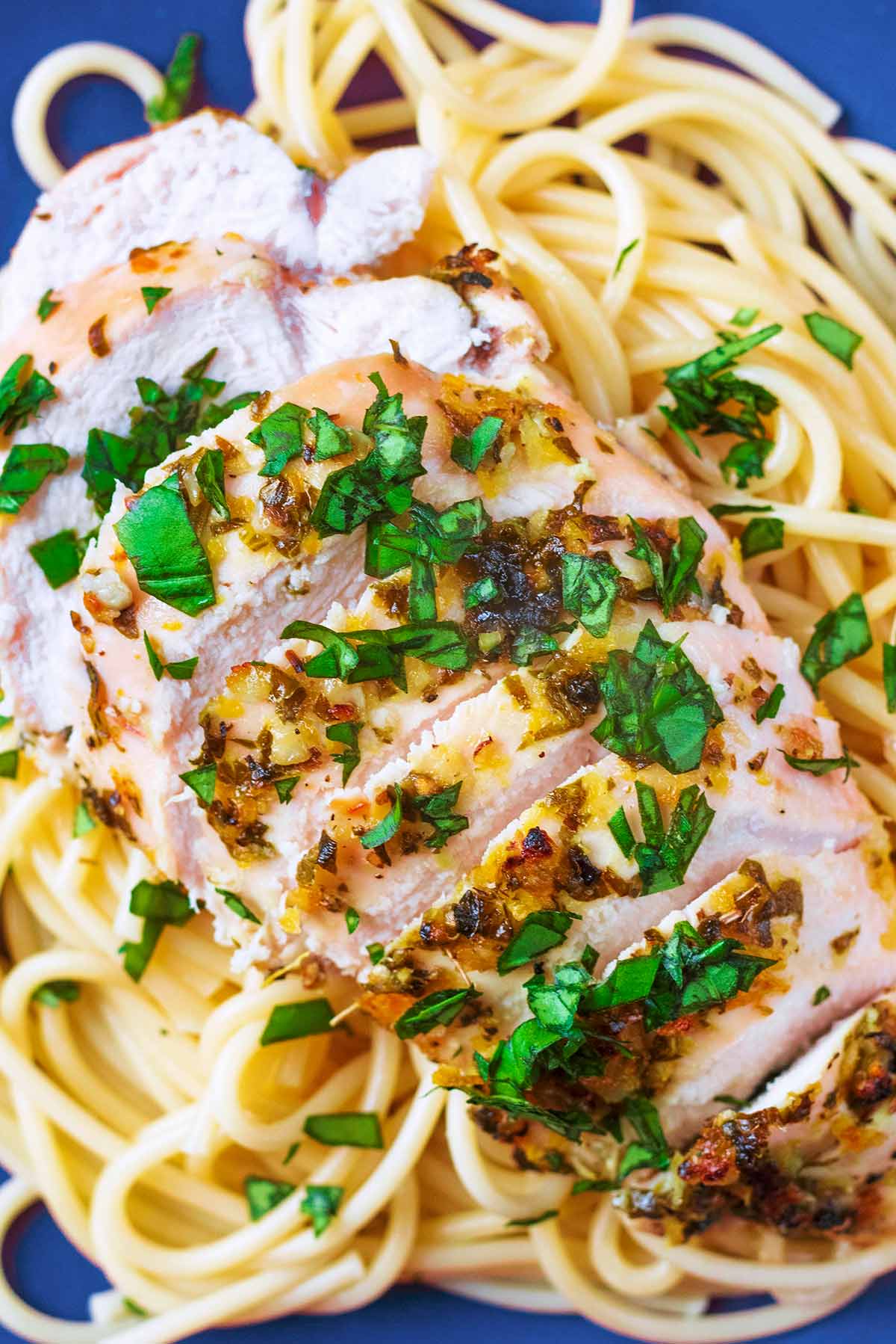 Sliced cooked chicken breast on top of spaghetti.