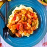 Slow Cooker Spanish Chicken on a blue plate with a knife and fork.
