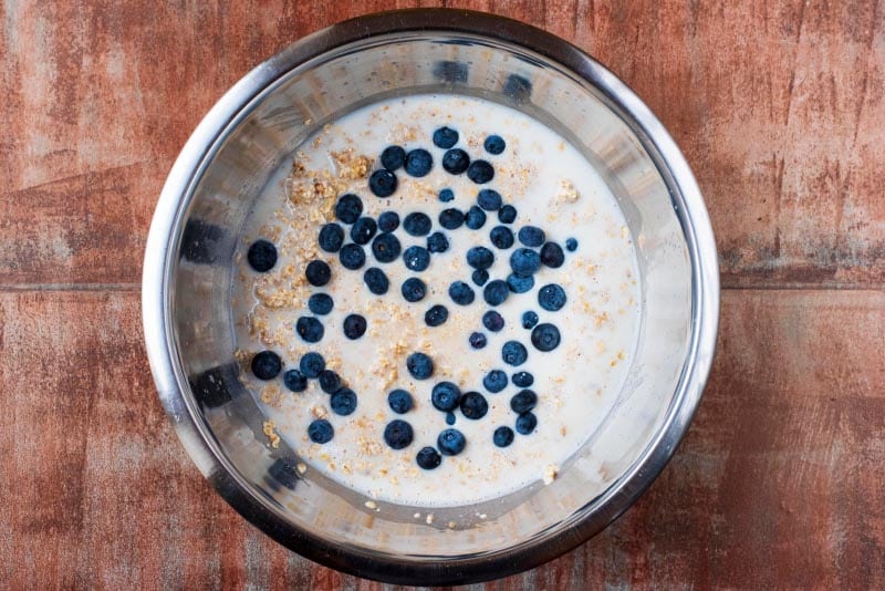 Oats, milk and blueberries in a mixing bowl.