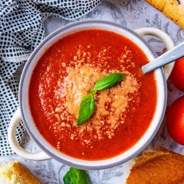 Tomato and Basil Soup topped with grated cheese and two basil leaves.