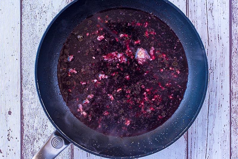 A frying pan with a deep purple sauce cooking in it.