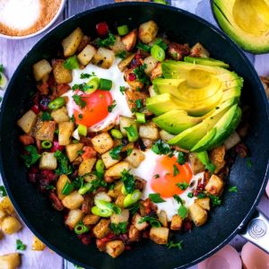 Breakfast Hash in a frying pan with sliced avocado.