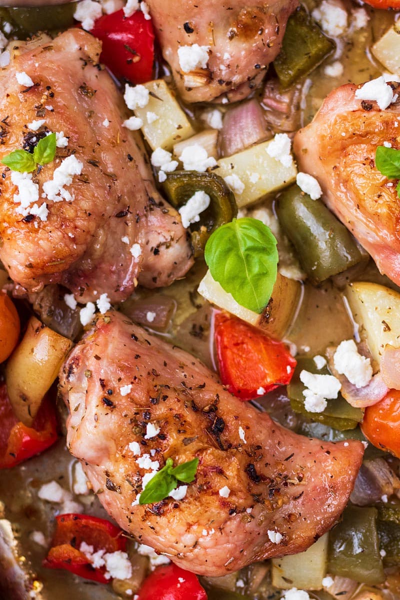 Baked chicken thighs in a sheetpan with chunks of vegetables.