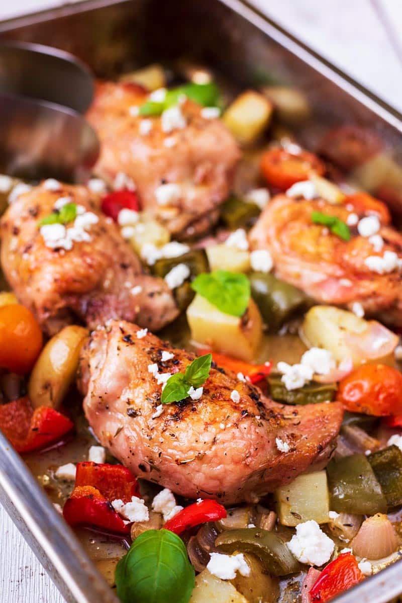 A large baking tin with chicken thighs and chunky vegetables.