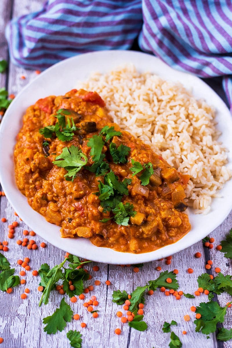 Curry and rice in a bowl with red lentils scattered around.