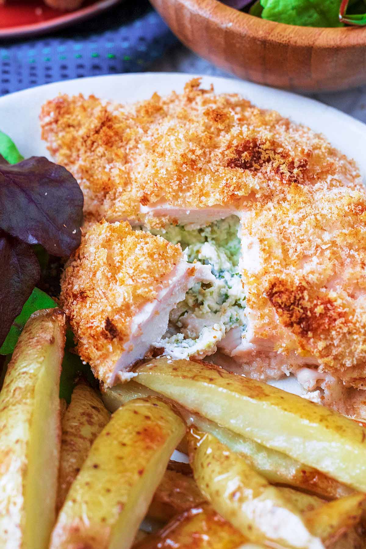 A chicken Kiev, cut open showing a cheese and herb filling.