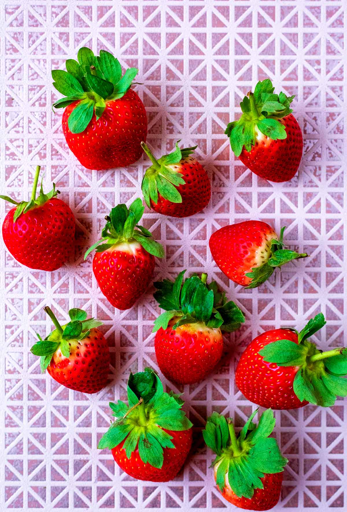 Eleven fresh strawberries on a tiled surface.