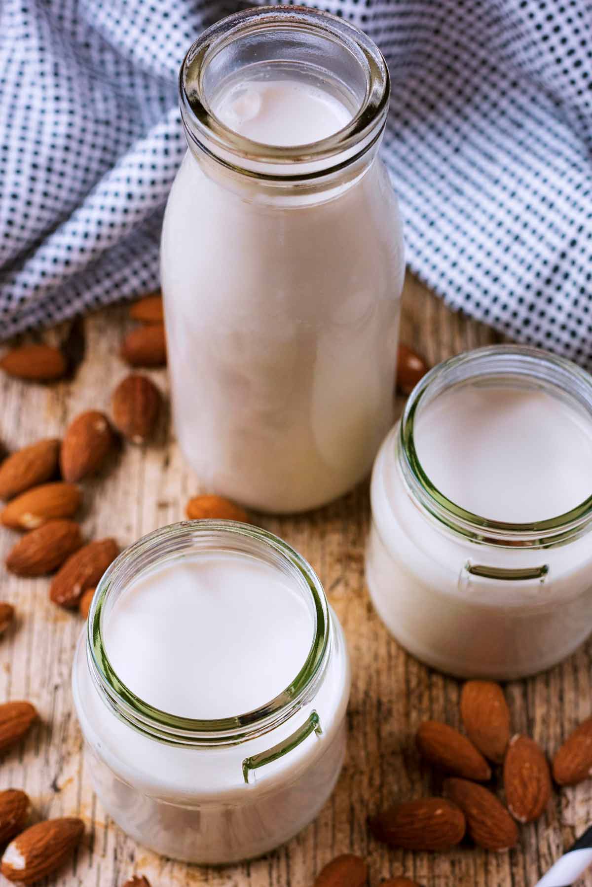 Jars of almond milk next to a black and white spotted towel.