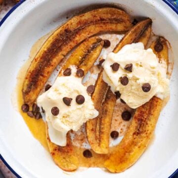 Honey baked bananas in a dish topped with balls of ice cream and chocolate chips