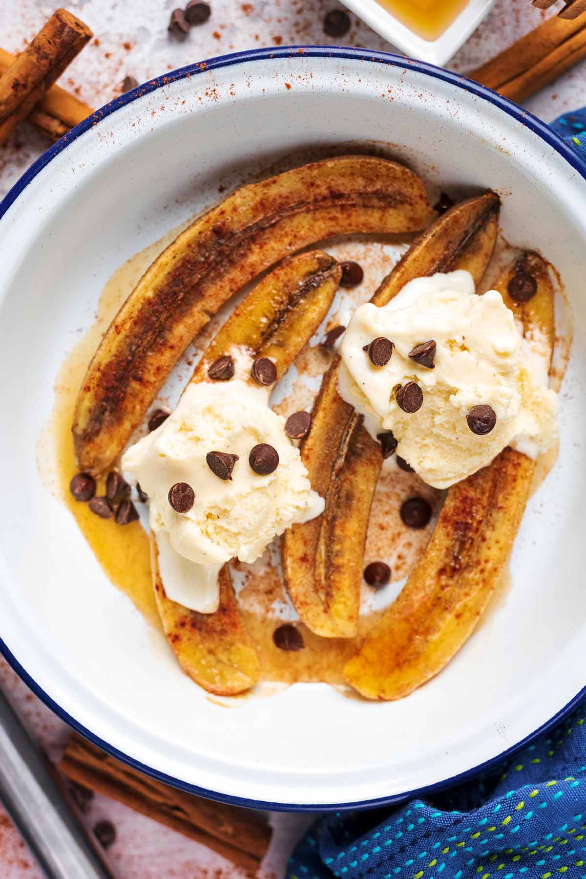 A round baking dish containing baked bananas, Ice cream and chocolate chips.