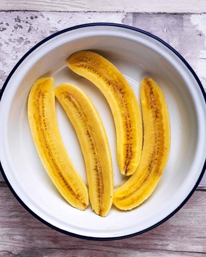 Four banana halves in a round dish.