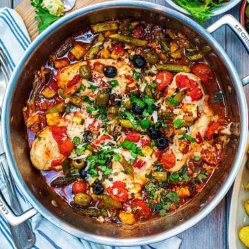 Italian Chicken in a large silver pan topped with chopped basil and parmesan shavings.