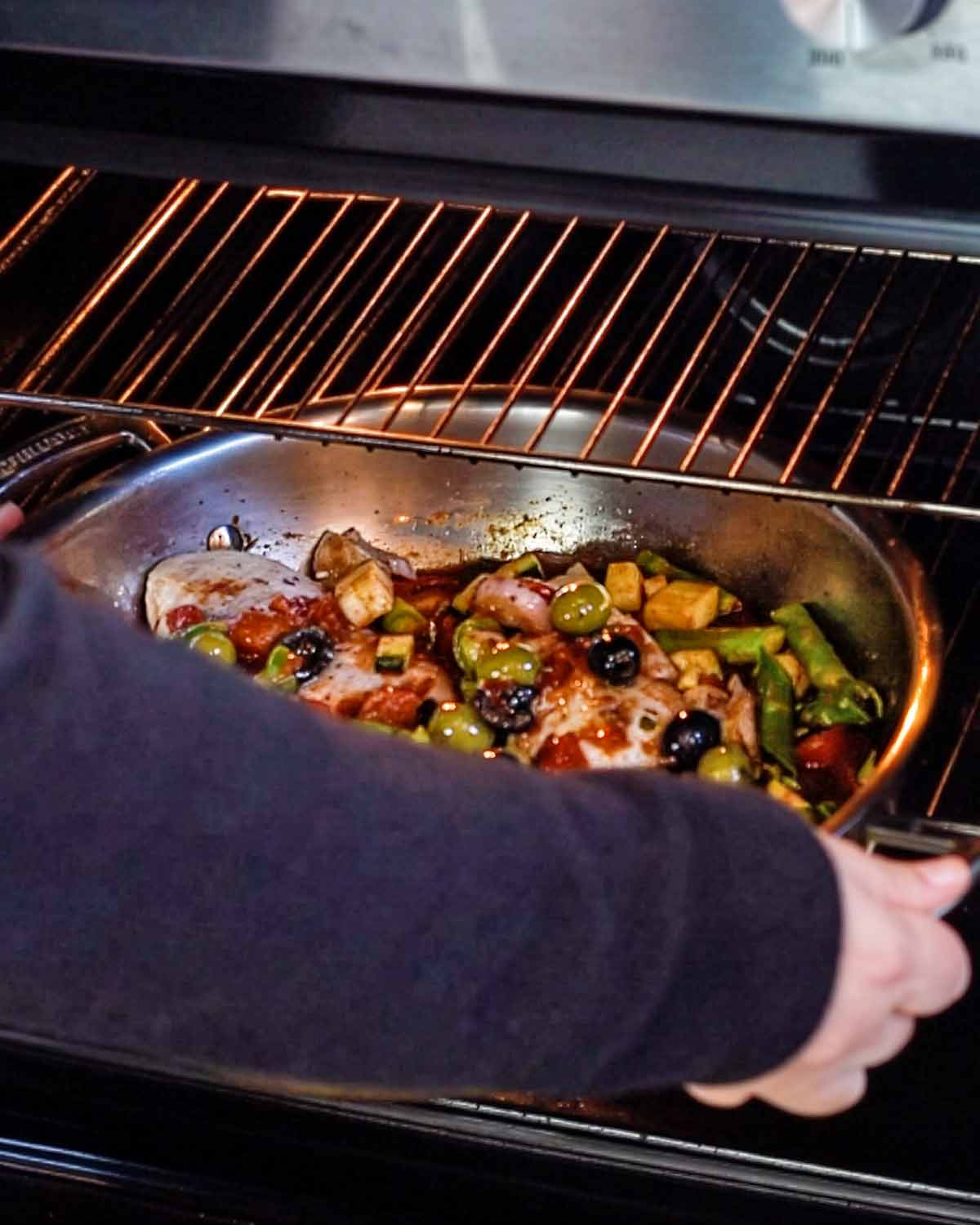 Someone putting a large pan into an oven.